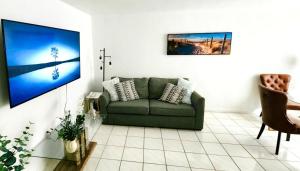 a living room with a green couch and a tv at Bayfront Apartment Breathtaking Views- one bedroom w balcony- living room -Free Parking in Miami Beach