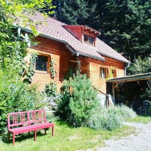 Lodge bien être et nature في Soultzeren: منزل خشبي أمامه جلسة حمراء