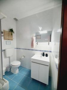 Baño blanco con aseo y lavamanos en Casa Olívia en Carrapateira