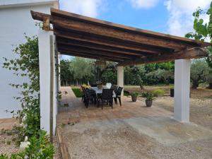 a patio with a table and chairs under a wooden pergola at Lo raconet in L'Ampolla