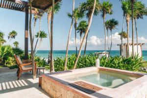a bath tub sitting next to a beach with palm trees at Mi Amor Boutique Hotel-Adults Only in Tulum