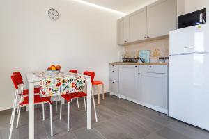 Lavender, Lighthouse, Sunrise Apartments - Kuća&More House No13 في كرك: مطبخ مع طاولة مع كراسي حمراء وثلاجة