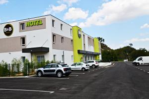 un hotel con coches estacionados en un estacionamiento en B&B HOTEL Alès - Pôle Mécanique, en Saint-Martin-de-Valgalgues