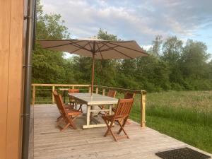a table and chairs with an umbrella on a deck at Les Jours Heureux Tiny House in Villers-le-Gambon