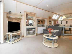 a living room with a television and a couch and a table at Coed Llai Lodge in Holyhead