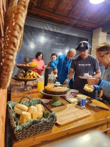 eine Gruppe von Menschen, die um einen Tisch mit Essen stehen in der Unterkunft Pousada La na Roça in Paraisópolis