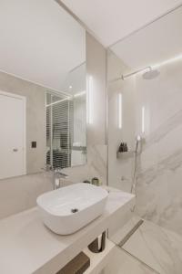 y baño blanco con lavabo y ducha. en Grand Brizo Bel Air en Buenos Aires