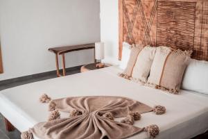 a large white bed with a blanket and pillows at Che Zipolite Hostel & Naked Beach Club in Zipolite