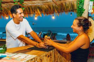 een man en een vrouw die handen schudden aan een bar bij Che Zipolite Hostel & Naked Beach Club in Zipolite