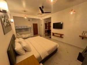 Rihiveli Residence Thoddoo في ثودو: غرفة نوم بسرير وتلفزيون بشاشة مسطحة