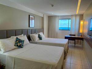 Habitación de hotel con 2 camas y escritorio en HY Apartments & Hotels, en Recife