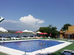 a large swimming pool with chairs and umbrellas at Aparthotel Las Palomas in La Puebla de los Infantes