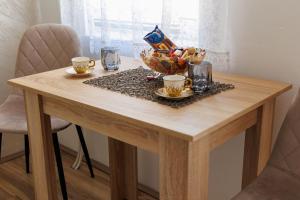 a wooden table with cups and a bowl of food on it at Apartman Relax in Šabac