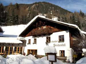 un edificio ricoperto di neve con una montagna sullo sfondo di Hotel Gasthof Stuibenfall a Niederthai