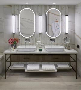 uma casa de banho com dois lavatórios e dois espelhos em Mandarin Oriental Palace, Luzern em Lucerna