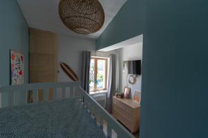une chambre bleue avec un lit bébé et une fenêtre dans l'établissement Le Cabanon - Les pieds dans l'eau - Calanques - Wifi, à Ensuès-la-Redonne
