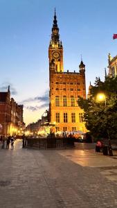 um grande edifício com uma torre de relógio ao anoitecer em Baltic Gdansk OLD TOWN em Gdańsk