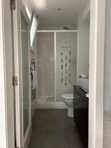 ein weißes Bad mit einer Dusche und einem WC in der Unterkunft Charmoso estúdio perto da praia in Parede