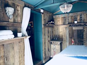 a bedroom with wooden walls and a bed with a window at The Nook at Blue Door Barns in Beddingham