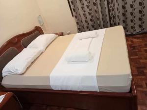 een bed met witte lakens en een houten frame bij Loidas place in Talisay