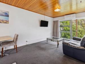 uma sala de estar com um sofá e uma mesa em ASURE Brookvale Motel em Wanaka