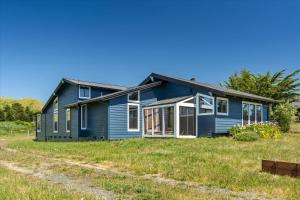 a blue house on a grassy field at The Bodega House - New Rental Near Salmon Creek in Bodega Bay