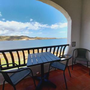 una mesa y sillas en un balcón con vistas al agua en Apto POBLET by MENORCAHOST - Vistas únicas al mar en Playas de Fornells, en Es Mercadal