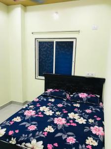 a bedroom with a bed with a floral comforter and a window at MO Furnished Guest House in Hyderabad
