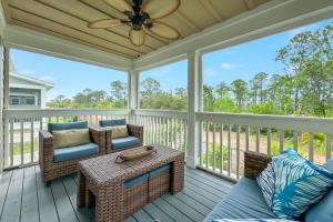 a screened porch with chairs and a table and a ceiling fan at Carlinga Cottage at Lost Key Golf & Beach Club in Pensacola