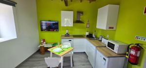 a kitchen with green walls and white cabinets and a table at Casa do Avô José Mota in Santa Cruz das Flores