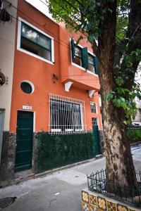 an orange building with green doors next to a tree at Rio Deal Guest House in Rio de Janeiro