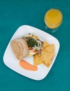 une plaque avec un sandwich, des chips et un verre de jus d'orange dans l'établissement Hostal La Mariapolis, à Necoclí