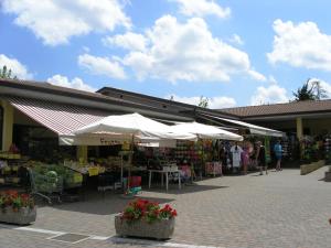 a market with white umbrellas in front of a building at Camping Bella Italia in Peschiera del Garda
