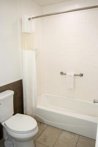 a bathroom with a white toilet and a tub and a sink at Americas Best Value Inn Harlingen in Harlingen