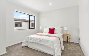 a white bedroom with a large bed and a window at Holiday Home at Huia Road in Auckland