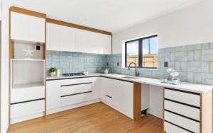 a kitchen with white cabinets and a sink at Holiday Home at Huia Road in Auckland