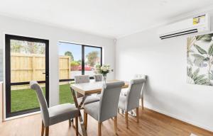 a dining room with white walls and a table and chairs at Holiday Home at Huia Road in Auckland