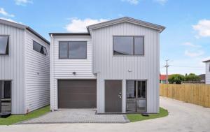 a white house with a garage at Holiday Home at Huia Road in Auckland