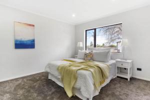 a white bedroom with a bed and a window at Holiday Home at Huia Road in Auckland