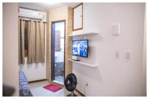 a room with a mirror and a tv on a wall at Promocional 3 Pessoas Vila Praia do Forte in Mata de Sao Joao