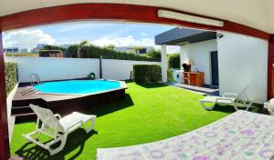 un patio trasero con piscina y césped verde en Peter Love House en Ericeira