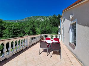Un patio con una mesa y sillas en un balcón. en Apartment Nenad, en Tribalj
