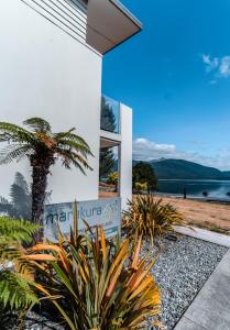 a house with a palm tree in front of a building at Marakura Deluxe Motel in Te Anau