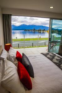 Schlafzimmer mit einem Bett und Blick auf das Wasser in der Unterkunft Marakura Deluxe Motel in Te Anau