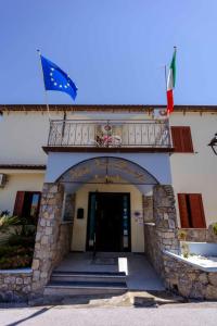 un edificio con balcón y banderas. en Hotel Villa Principe, en San Nicola Arcella