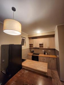 kuchnia z drewnianymi szafkami i czarną lodówką w obiekcie RoomsApartments PopCOURT w mieście Pančevo
