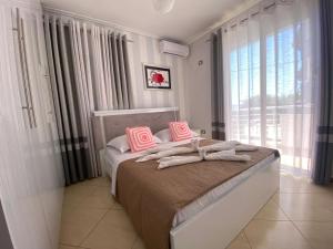 a bedroom with a bed with pink pillows on it at Olive Tree Apartment in Sarandë
