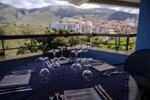 a table with wine glasses sitting on top of a balcony at Hotel Villa Principe in San Nicola Arcella