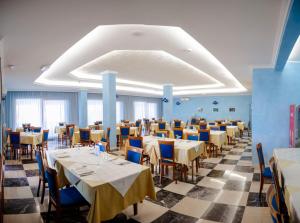 una sala da pranzo con tavoli e sedie e un pavimento a scacchi di Hotel Villa Principe a San Nicola Arcella