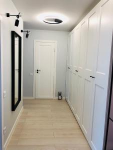 a hallway with white cabinets and a mirror at Bisou Elsa Apartment in Narva-Jõesuu